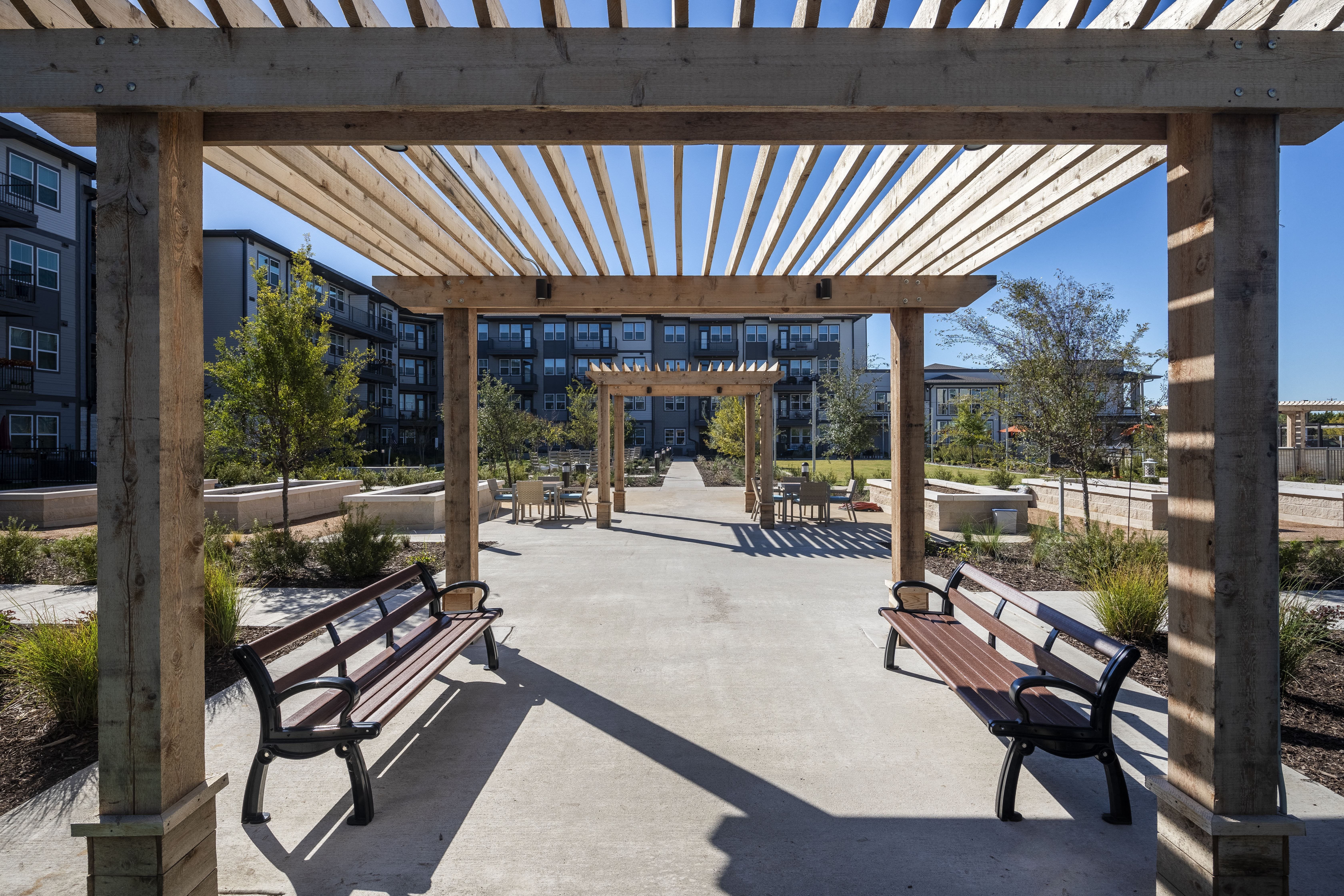 a covered area with benches and a building in the background
